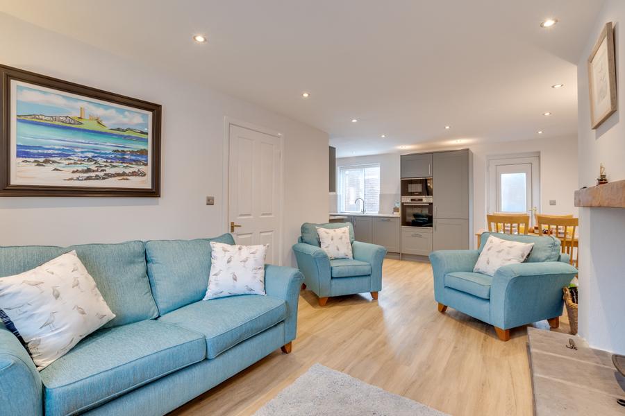 Sitting area with sofas and armchair looking through to the kitchen
